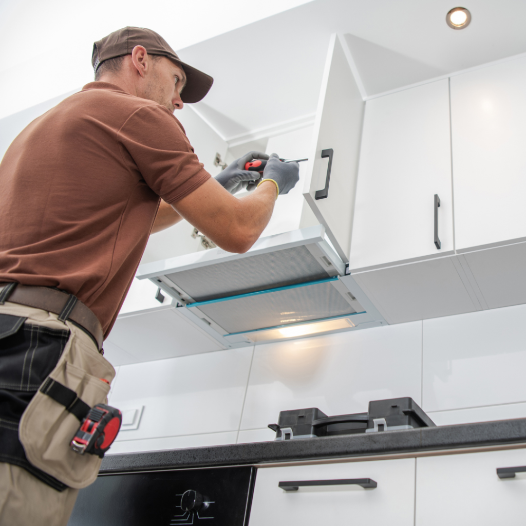 A carpenter installing cabinets in a modern kitchen